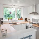 Kaminofen brennt in Wohnraum mit Holzdielen und Blick in Schlafzimmer.