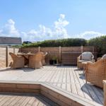 Terrasse mit Sitzgruppe und Tisch, umgeben von Holzgeländer und Hecke.