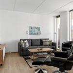 Dining area with table, chairs, and view to balcony. Wall art and radiator visible.