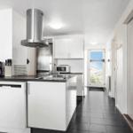 Modern kitchen with stainless steel appliances, white cabinets, and black countertops.