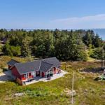 Rotes Ferienhaus mit großem Glasbereich und Terrasse im Grasland.
