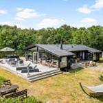 Terrasse mit Tisch, Stühlen, Sonnenschutz und Glasgartenhaus. Grill und Pflanzen sind vorhanden.