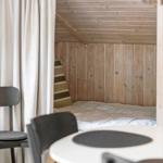 Ein Wohnzimmer mit Holzwänden, einem schwarzen Sofa und einem weißen Tisch.