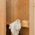 Sauna mit Holzbank und Badeeimer. Außenbereich mit Tisch und Stühlen.