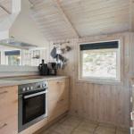 Küche mit Holzwand, Fenster, Spüle, Herd und Mikrowelle.