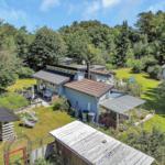 Wohnhaus mit weißen Holzwänden, Tür und Terrasse. An der Wand hängt ein Bild.