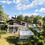 Terrasse mit Holzdielen, Sitzbank aus Paletten, Tisch und Stühle, zwei Sonnenschirme und Blick in den Garten.