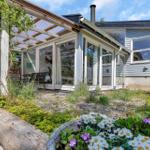 Ein Haus mit Terrasse, Garten und Blick auf Bäume.
