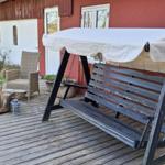 Hinterhof mit Gartenmöbeln, Terrasse und roter Holzwand mit Fenstern.