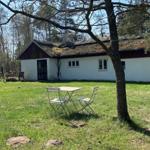 Haus mit strohgedecktem Dach und grünem Rasenfeld umgeben von Bäumen.
