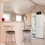 Wohnzimmer mit Sofa, Sessel und großen Fenstern. Holzwände und -decke.