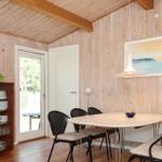 Wohnzimmer mit Holzwand, zwei Ledersessel und großem Fensterbereich.