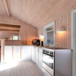 Schlafzimmer mit Holzwand, Fenster mit Jalousie und Bett mit weißen Kissen.