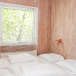 Zimmer mit Bett und Kinderbett mit Winnie the Pooh-Motiv, Holzwand und Fenster mit Jalousie.