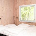 Badezimmer mit Dusche, Toilette und Waschbecken. Weiße Wände und Holzdecke.