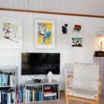 Wohnzimmer mit Sofa, Sessel und großem Fensterblick auf Wald