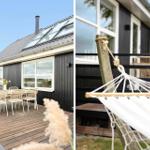 Schwarzes Haus mit Terrasse, umgeben von Grün und Blick auf das Meer.