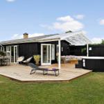 Schwarzes Haus mit Terrasse, Liege, Hot tub und Garten.