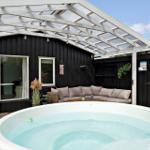Hinterhof mit Whirlpool, Sitzbank und überdachtem Bereich. Schwarze Holzwand und Terrasse.