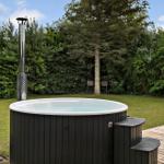 Außenwhirlpool mit Holzterrasse und grünem Gartenhintergrund.