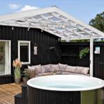 Holzterrasse mit Whirlpool, Sonnenschutz und Gartenmöbeln.