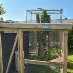 House with wooden terrace, grill, umbrella, and garden.