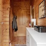Wooden wall with desk, bookshelf, and lamp. Wood-burning stove with fire.