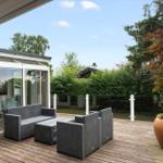 Terrasse mit Sitzgelegenheiten und Blick auf Garten und Bäume.