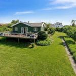 Green vacation house with terrace and garden. Background: other houses and trees.