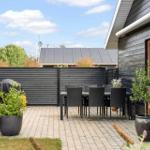 Terrasse mit Sitzgruppe und Blick auf Wald. Modernes Haus mit Glasfassade.