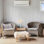 Two wicker chairs and a fur ottoman are by a window.