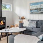 A living room with gray sofa, fireplace, and wall painting above the sofa.