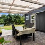 Patio with table and chairs under roof, view of green garden