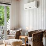 Two wicker chairs and a fur ottoman are in a room with wood paneling and a window.
