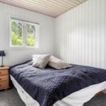 Bedroom with bed, nightstand, and window overlooking greenery.