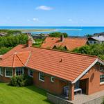 Ein Haus mit rotem Dach und grünem Garten. Blick auf das Meer und die Umgebung.