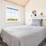 Schlafzimmer mit Bett, Fenster und Nachttisch. Wandverkleidung und Holzdecke.
