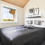 Schlafzimmer mit Bett, Fenster und Wandregal mit Dekoration.