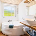 Bad mit Badewanne, Waschbecken und Fenster mit Grünblick.