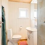 Badezimmer mit Toilette, Waschbecken und Dusche mit Glaswand.