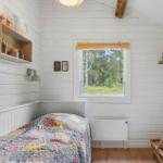 Badezimmer mit Dusche, Waschbecken und Holzregal.