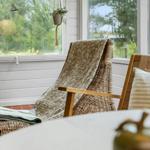 Wohnzimmer mit schwarzer Couch, Holzstühlen und einem runden Tisch auf Teppich.