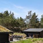 Ein Haus mit Grasdach, Terrasse und Garten. Möbel sind draußen platziert.