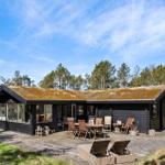 Holzhaus mit grüner Dachdeckung, umgeben von Bäumen und Gras