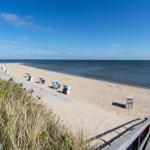 Strandkörbe mit blau-weißen Streifen stehen auf sandigem Strand.