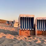 Wellen brechen an einem Strand unter blauem Himmel mit weißen Wolken.