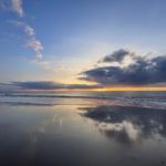 Strand mit Strandkörben und Holzsteg. Blick auf das Meer unter blauem Himmel.