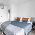 Schlafzimmer mit Bett, Nachttisch und Kleiderschrank. Boden aus Holz.