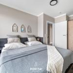 Schlafzimmer mit Doppelbett, Nachttisch, Kleiderschrank und dekorativen Bildern an der Wand.