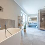 Bad mit freistehender Badewanne, Dusche und Waschtisch. Wanddekoration mit Fischmotiv.
